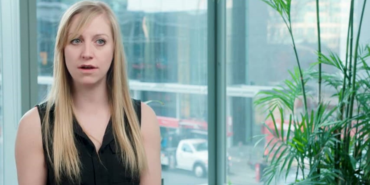 A women sits in front of an office window giving an interview